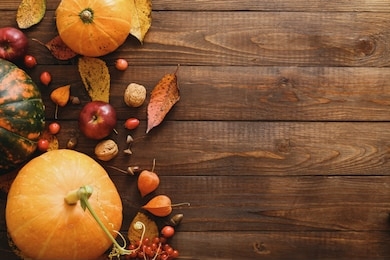 autumn composition. pumpkins, fallen leaves, apples, red berries, walnuts on wooden table. happy thanksgiving concept. flat lay, top view, copy space