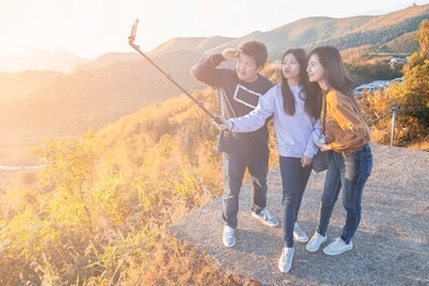 group of teenagers taking a selfie with a beautiful mountain view in the morning at khao chang phuak. kanchanaburi, thailand.