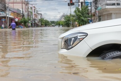 car driving on a flooded road, the broken car is parked in a flooded road.