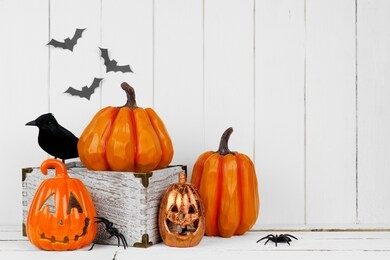 halloween display with jack o lantern decor and pumpkins against a rustic white wood background. copy space.