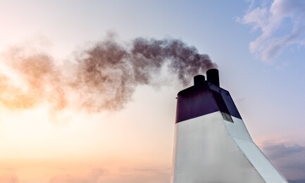 exhaust pipes of ferry boat with black thick smoke coming out, blue sky on background.