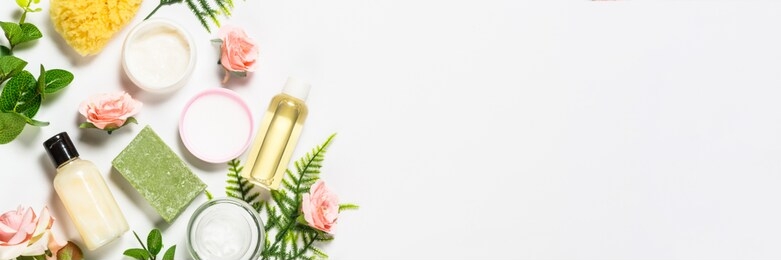 natural osmetics, skin care product with green leaves and roses. flat lay image on white. long banner format.