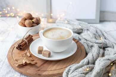 cup of coffee, brown sugar, knitted scarf, garland. autumn mood. cozy autumn composition. hygge concept. soft focus