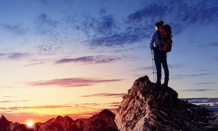 image of young man mountaineer standing atop of rock