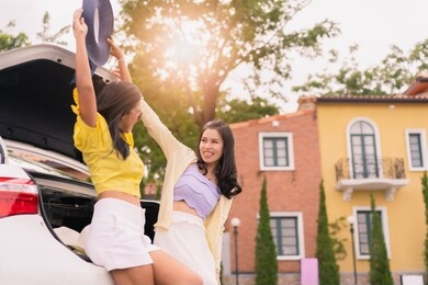 two young asian woman smiling enjoy sitting at car back in day trip