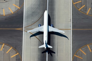 aerial view of narrow body aircraft departing airport runway.