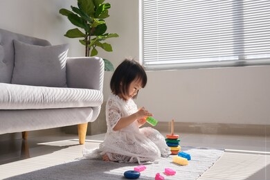cute little girl playing with building blocks on floor at home