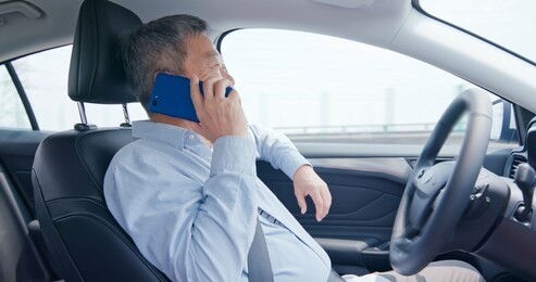 asian elderly man speak phone and drive an auto self-driving smart car in highway