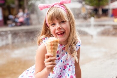 cute happy blonde little girl eating ice cream in park. 