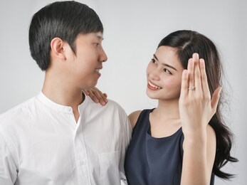 happy woman showing engagement ring after proposal while is cuddling her boyfriend.