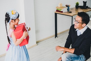 asian father and mother give a red box gift to daughter on the eve of christmas and new year's day.family happiness time concept.