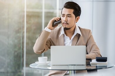 young business man talking on mobile phone and using laptop