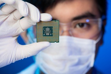 cropped image of an engineer showing a computer microchip on the foreground