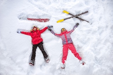 skier and snowboarder are lying on snow with ski and snowboard and having fun. aerial photo