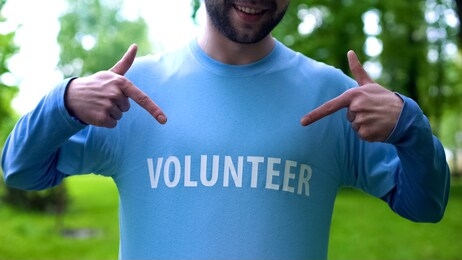 smiling man pointing at volunteer word on t-shirt, wildlife preservation, earth