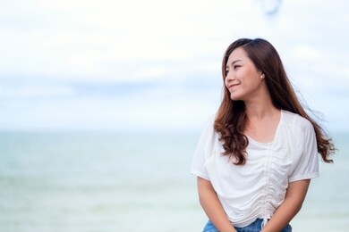 a beautiful asian woman sitting by the sea
