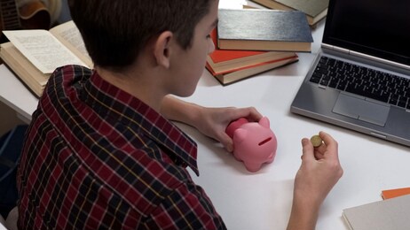 teenager holding coin going to put into piggy bank, saving money, finances