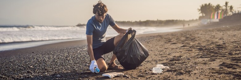 young man cleaning up the beach. natural education of children banner, long format
