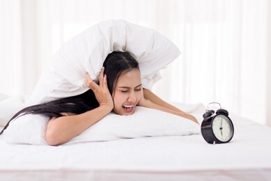 bored young asian woman hates getting stressed waking up early 6 o'clock on bed,alarm clock