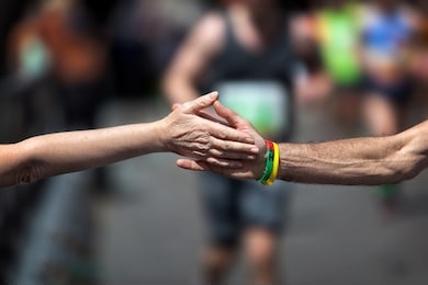 support during the physical effort of the race. a woman from the audience at her arm and touches the hand of an athlete running the marathon.