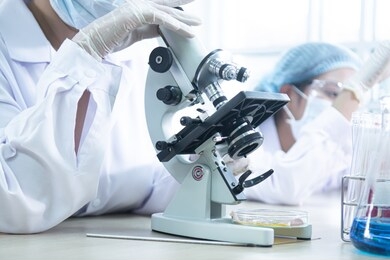 lab assistant and veterinarian examining tissues sample from  under the microscope and include glass tubes, many test tubes in the laboratory which contain various colors of liquid.