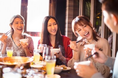 happy young friends eating hot pot in restaurant 