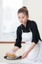 vertical image of a young chambermaid preparing breakfast for the guests 