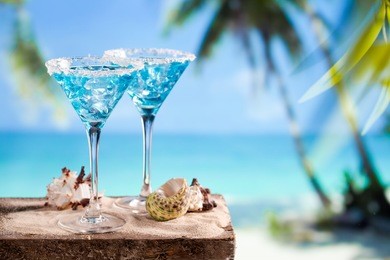 fresh cocktail with blue curacao on beach background