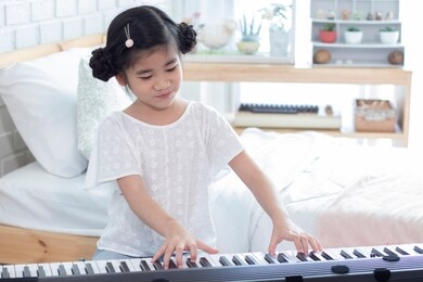 creative activities develop children's skill. education and music concept.  young asian girl concentrate to practice with electric piano (synthesizer) or keybords to be a professional pianist.