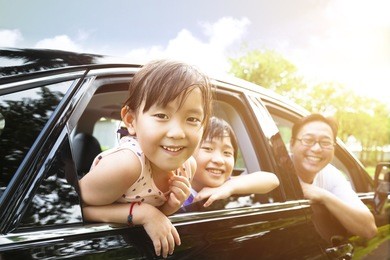 happy little girl with family sitting in the car 