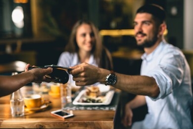 man paying for lunch in restaurant with mobile phone