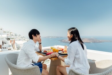 beautiful couple having breakfast on vacation on santorini island, greece. 
