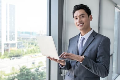 successful man with laptop in modern white office with glass around