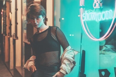 serious fashion tomboy teen hipster short hairstyle gen z girl wear stylish clothes glasses stand near neon street sign, female model woman look at camera in city night light 80s style glow, portrait