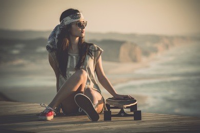 beautiful young woman sitting over a skateboard