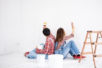 young asian couple in yom-bear and plaids shirts in concept couple help painting a new color the room renovation in thailand
