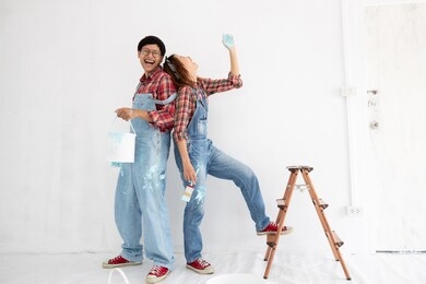 young asian couple in yom-bear and plaids shirts in concept couple help painting a new color the room renovation in thailand