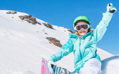 little cute girl snowboarding at ski resort in sunny winter day. 