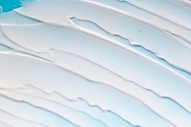 white cosmetic cream diagonal strokes on blue background. face cream, body lotion, moisturizer smudge. beauty product texture
