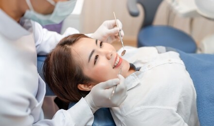 closeup woman having dental teeth examined dentist check-up via excavator in clinic her patient for beautiful smile