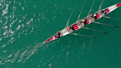 aerial drone photo of team of athletes rowing in sport canoe in tropical exotic lake