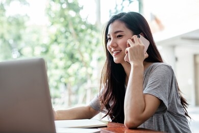 cute asian girl using phone on wooden table.