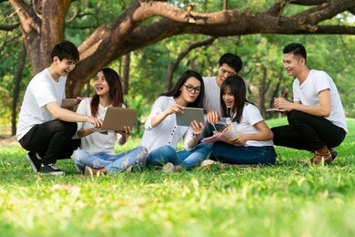 team of young students studying in a group project in the park of university or school. happy learning, community teamwork and youth friendship concept.