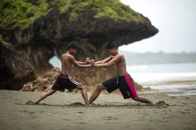 asians teens fighting on the beach. young men wrestle. filipino boys playing on the beach. 