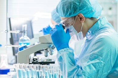 asian male scientist  use microscope to observe green plant in the laboratory