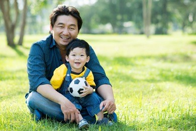 copy-spaced portrait of a father and his son sitting on the ground in the park