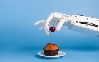 kitchen robotization. robot hand putting fresh cherry on top of the cupcake, blue background