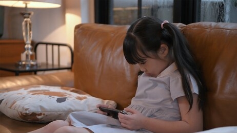 holiday concept. a young girl is playing with a mobile phone seriously. 4k resolution.