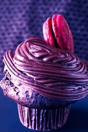 closeup of a cupcake with a red macaron, festive neon red and blue color split hue.