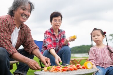 close up asian man, asian family picnic and cooking in garden, they grilling barbecue, they feeling happy in party activity, happiness family time